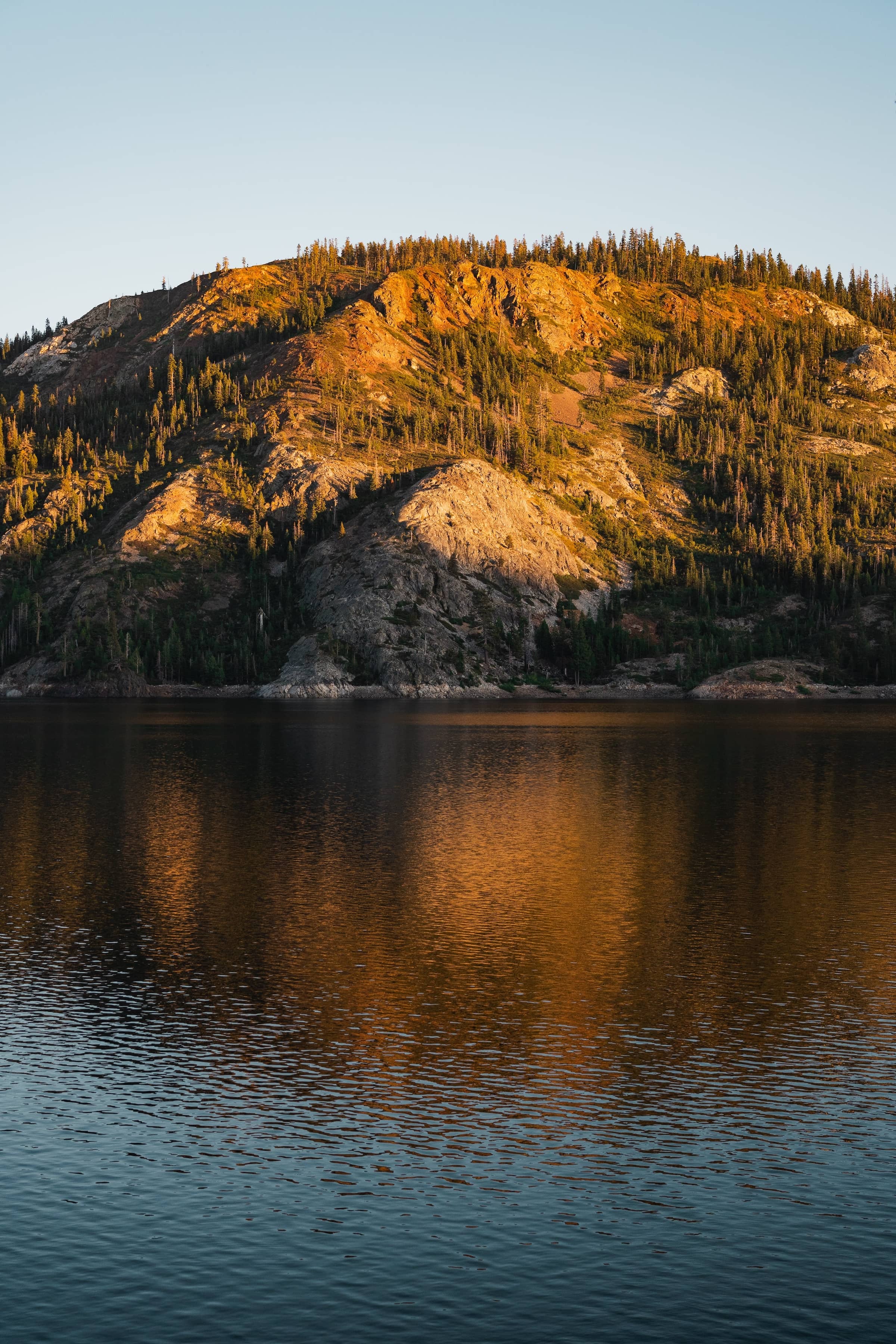 A vertical shot of the lake and mountains across the water on the shore showing majesty in the late evening light.