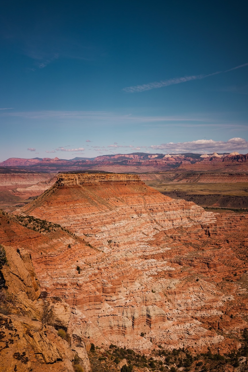 A striking view of layered red rock formations under a clear sky, showcasing the natural beauty and grandeur of a canyon landscape.