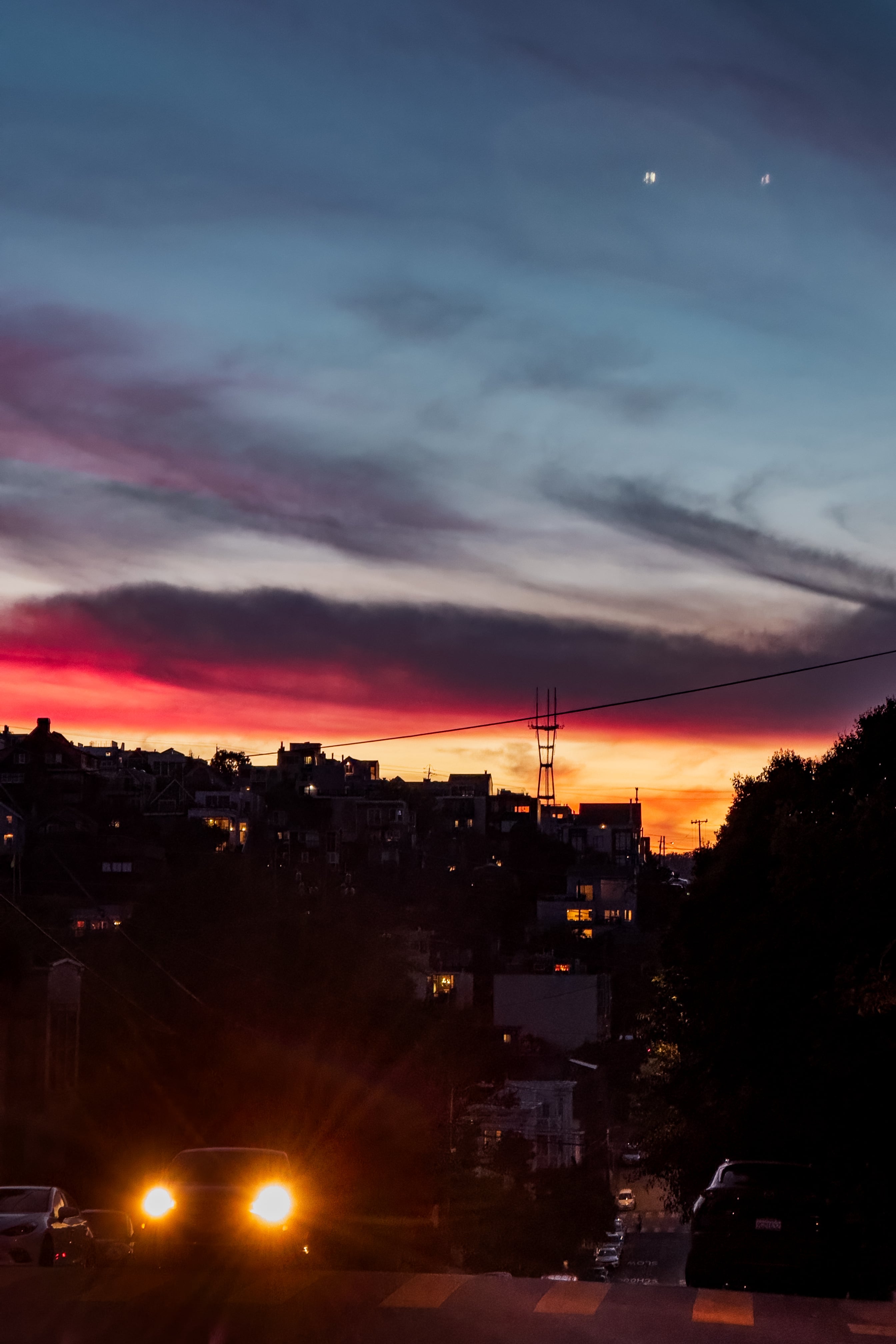 A sunset view of Sutro Tower in the distance in San Francisco, taken from high on a hill in Potrero Hill at dusk with orange and purple skies